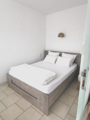 un lit avec des draps blancs et des oreillers dans une chambre dans l'établissement Plage des Chalets appartement T2+terrasse, à Gruissan