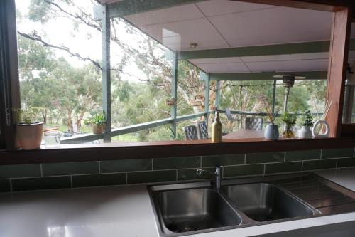 a kitchen with a sink and a large window at Allusion Farmstay Cellar House Heated Pool - Fire Pit - Pizza Oven - Pool Table - Sleeps 16 in Yankalilla