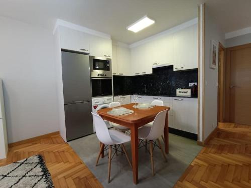 een keuken met een houten tafel en witte stoelen bij Acogedor apartamento en Vigo in Vigo