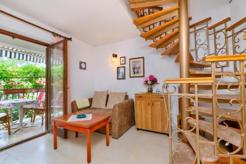 a living room with a couch and a spiral staircase at Apartments Marija in Mali Lošinj