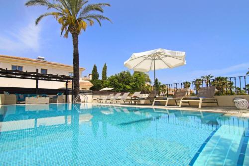 a swimming pool with a palm tree and an umbrella at Villa Oceania - Beachfront in Paralimni