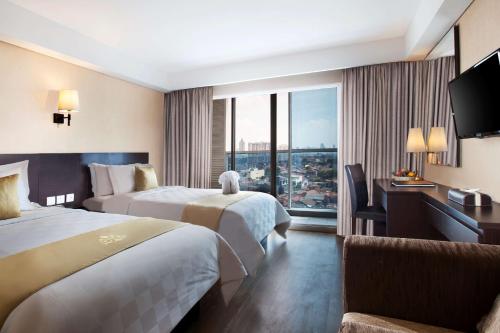 a hotel room with two beds and a window at Best Western Premier The Hive in Jakarta