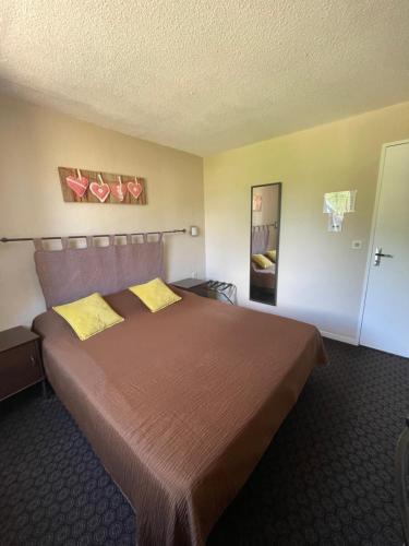 a hotel room with a large bed with yellow pillows at Hôtel Restaurant Les Falaises in Bouziès
