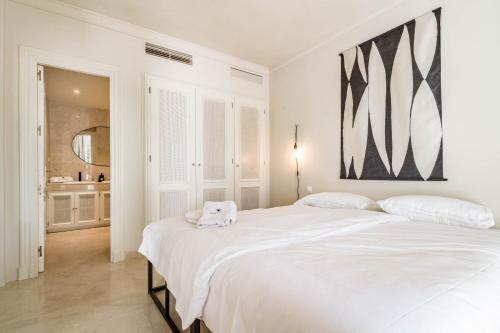 ein weißes Schlafzimmer mit einem großen Bett und einem Badezimmer in der Unterkunft Fully Renovated Modern 2 bedroom apartment in Aloha Pueblo in Marbella
