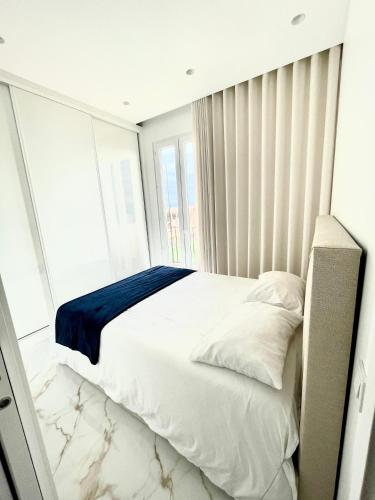 une chambre avec un lit avec des draps blancs et une fenêtre dans l'établissement Luxueux appartement aux portes de Monaco - CAP D AIL, à Cap d'Ail