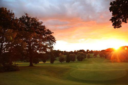 a sunset on a golf course with a green at Shaw Hill Hotel Golf And Country Club in Chorley