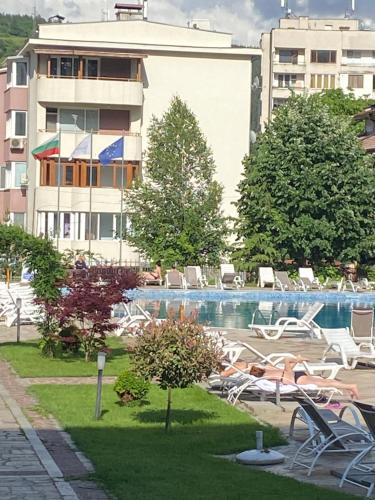 a swimming pool with chairs and a building at Апартамент за гости in Devin