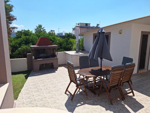 a patio with a table and chairs and an umbrella at Villa Maria in Haraki