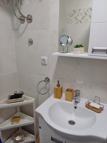 y baño con lavabo blanco y espejo. en Apartman Silver Lux Srebrno jezero, en Veliko Gradiste