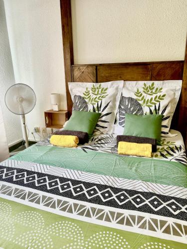 łóżko z zielonymi i białymi poduszkami w obiekcie Le P'tit Baldaquin w mieście Saint-Denis