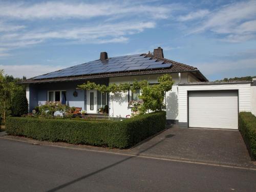a white house with a solar roof and a garage at Apartment in Niederehe near the forest in Üxheim
