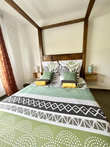 - une chambre avec un grand lit et une tête de lit en bois dans l'établissement Le P'tit Baldaquin, à Saint-Denis