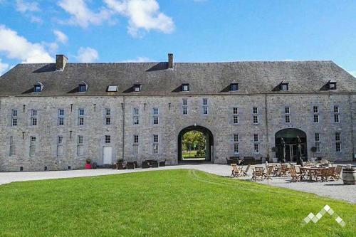 un gran edificio de piedra con césped delante en Dépendance du châteaux de Modave en Modave