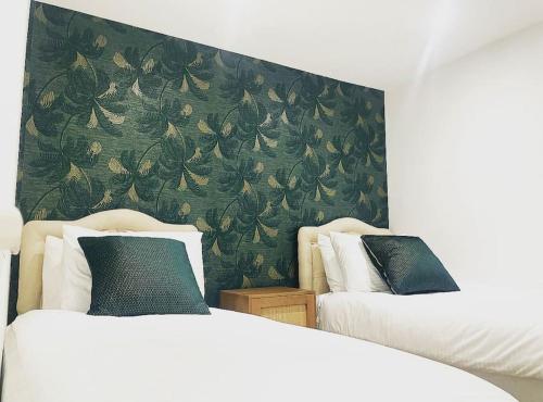 - une chambre avec 2 lits et un mur vert dans l'établissement The Elegant Abode Apartment 2023 NEW-BUILD, à Oxford
