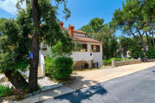 a house with a tree in front of a street at Apartments Marija in Mali Lošinj