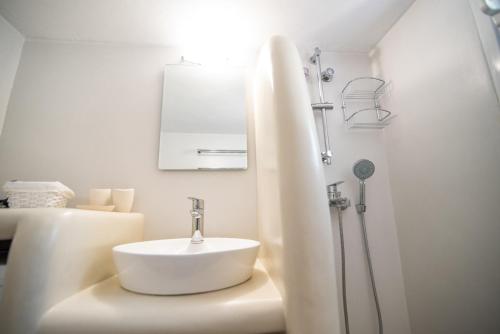La salle de bains blanche est pourvue d'un lavabo et d'une douche. dans l'établissement Izabella's House Naxos, à Mélanes