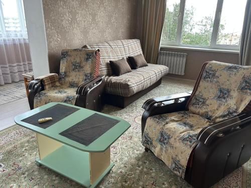 salon z 2 krzesłami, kanapą i stołem w obiekcie 14-38 вид на море лучший район w mieście Aktau