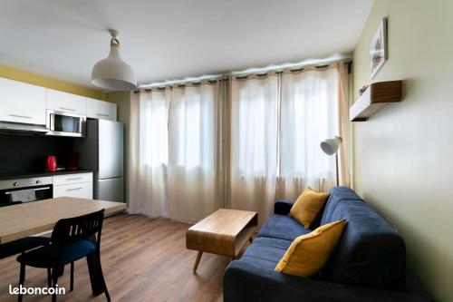 un salon avec un canapé bleu et une table dans l'établissement Le p'tit Flaubert- Quartier Coty, au Havre