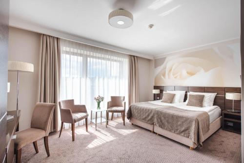 een hotelkamer met een bed en een tafel en stoelen bij Hotel Różany Gaj in Gdynia