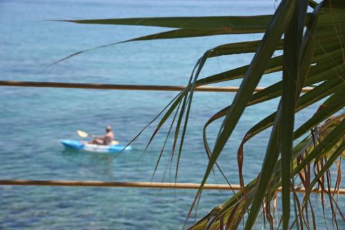 a man in a blue boat in the water at Paradisso Beach Villas in Zakynthos Town