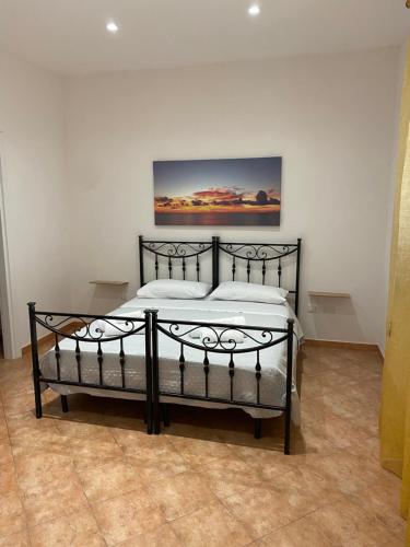 un letto nero in una stanza con un dipinto sul muro di ZEFIRO a Marsala