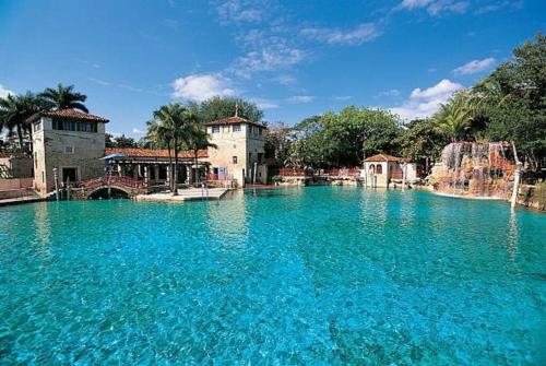 uma grande piscina de água azul em frente aos edifícios em My lovely home in Miami 15 minutes from the Beach em Miami