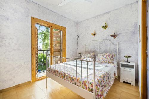 een slaapkamer met een bed en een raam met vlinders aan de muur bij Tu casita de la playa in Santa Pola