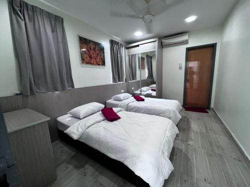 Habitación con 3 camas, sábanas blancas y almohadas rojas. en Naam Boutique Lodge, en Port Dickson