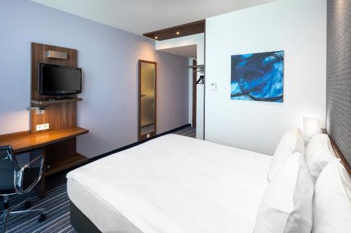 a room with a bed and a desk and a tv at Holiday Inn Express The Hague - Parliament by IHG in The Hague