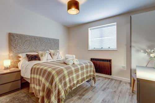 - une chambre avec un lit, une couverture et une fenêtre dans l'établissement Highlander Barn, à Minster Lovell