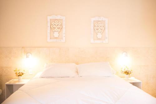 a bedroom with a white bed with two lights on it at Suítes no centro histórico in Petrópolis