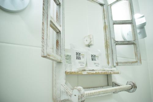 un espejo colgado en la pared de un baño junto a un lavabo en Suítes no centro histórico, en Petrópolis