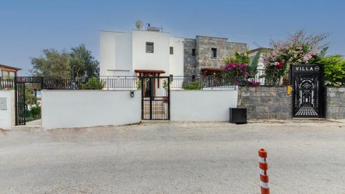 a white building with a gate in front of a street at Villa House Sea View Türkbükü in Bodrum City