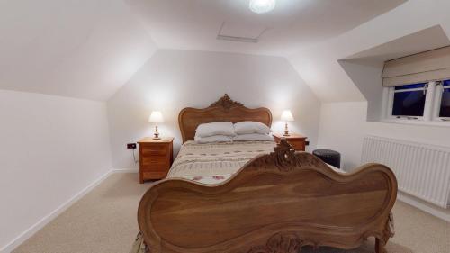 um quarto com uma grande cama de madeira e 2 candeeiros em Bushnells Cottage em Oxford