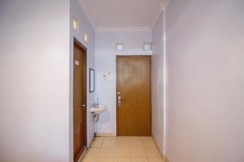 a bathroom with a toilet and a wooden door at Halona Residence near Pakuwon Mall Jogja Mitra RedDoorz in Yogyakarta