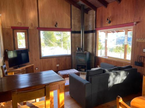 uma sala de estar com um sofá e uma mesa em Cabaña de Montaña em San Martín de los Andes