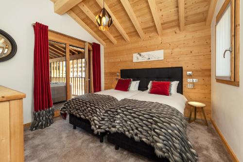 une chambre avec un grand lit avec des oreillers rouges dans l'établissement Colibri Penthouse, à Morzine