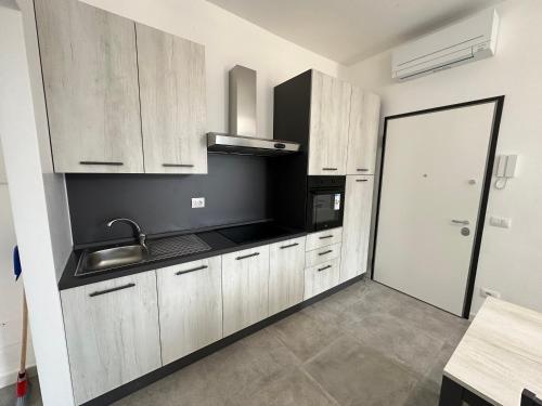 a kitchen with wooden cabinets and a sink and a door at LUX apartments STARS in Follonica
