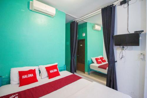 a room with a bed with red pillows and a tv at Halona Residence near Pakuwon Mall Jogja Mitra RedDoorz in Yogyakarta