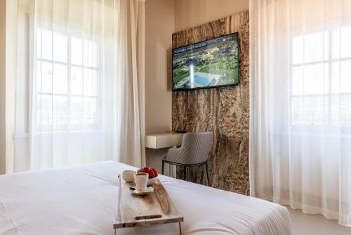 a hotel room with a bed and a tv on a wall at TENUTA FOGLIANI Resort & Natural Spa in Visciano