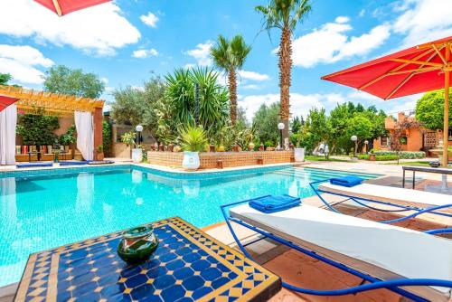 a swimming pool with two chairs and an umbrella at Villa Gardens Diafa in Marrakesh