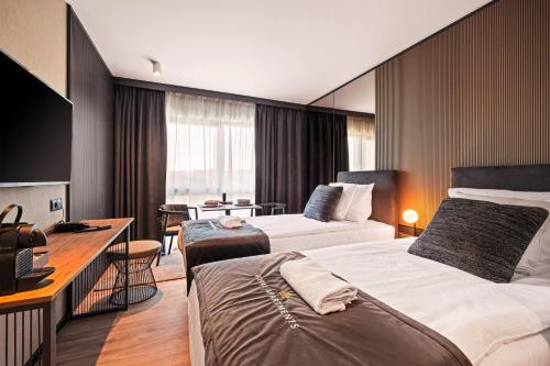 a hotel room with two beds and a desk at Royal Apartments - Boutique Residence Gdańsk in Gdańsk