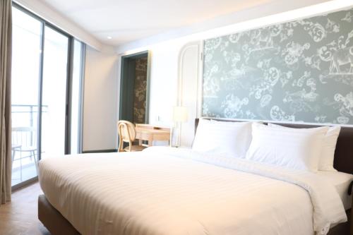 a bedroom with a large white bed and a desk at The Quarter Chaophraya by UHG in Bangkok