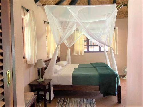 1 dormitorio con 1 cama con dosel en Family Lodge in Natural African bush - 2113, en Bulawayo