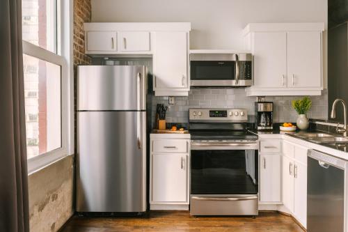 a kitchen with white cabinets and a stainless steel refrigerator at Sonder The Hogg Palace in Houston