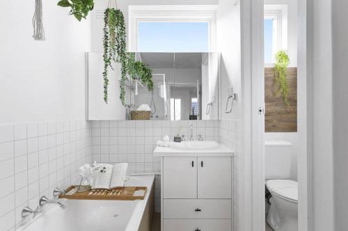 La salle de bains blanche est pourvue d'un lavabo et de toilettes. dans l'établissement Beachside Getaway on Selwyn, à Melbourne