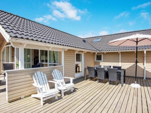 a wooden deck with chairs and an umbrella at 8 person holiday home in Hemmet in Falen