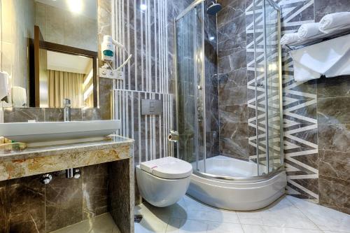 uma casa de banho com um WC, um lavatório e um chuveiro em Kilikya Hotel em Kizkalesi