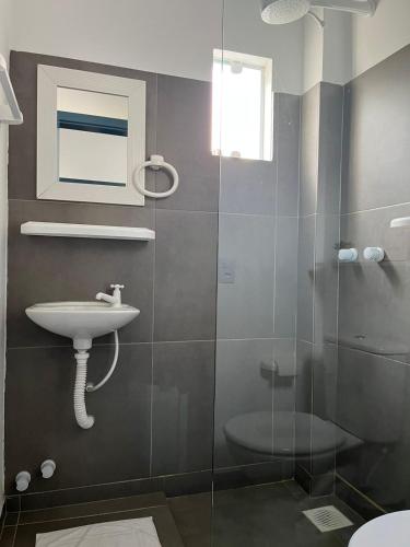 a bathroom with a sink and a glass shower at Pousada Silvestre in Tramandaí
