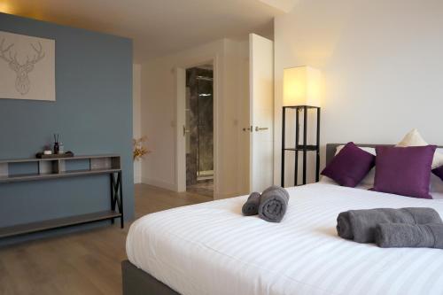a bedroom with a large white bed with purple pillows at Penthouse by the Ipswich Station in Ipswich